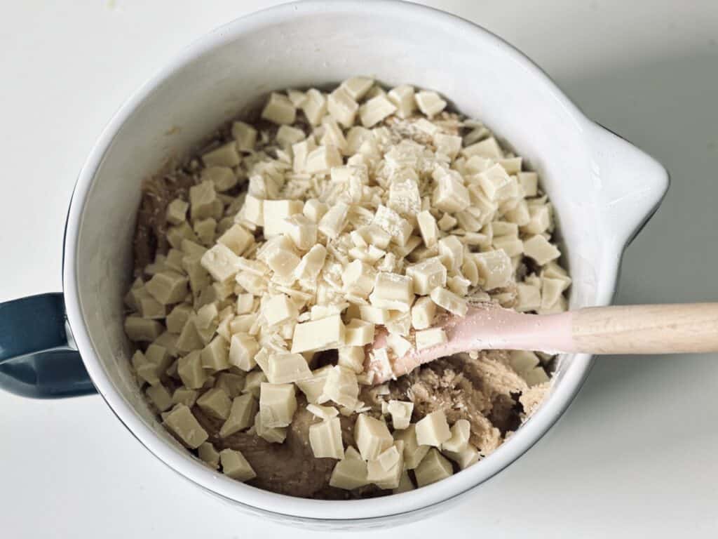 A large bowl filled with cookie dough and topped with white chocolate chunks.