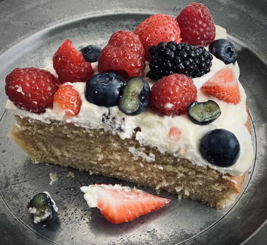 A slice of sponge cake topped with cream and fresh fruits