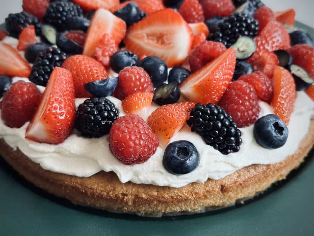 A brown sugar sponge cake topped with cream and fresh fruits.