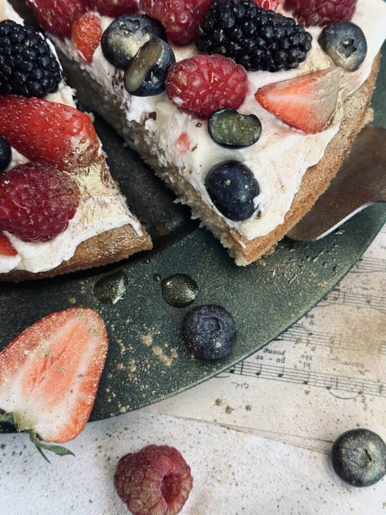 A slice of sponge cake with cream and berries as toppings.