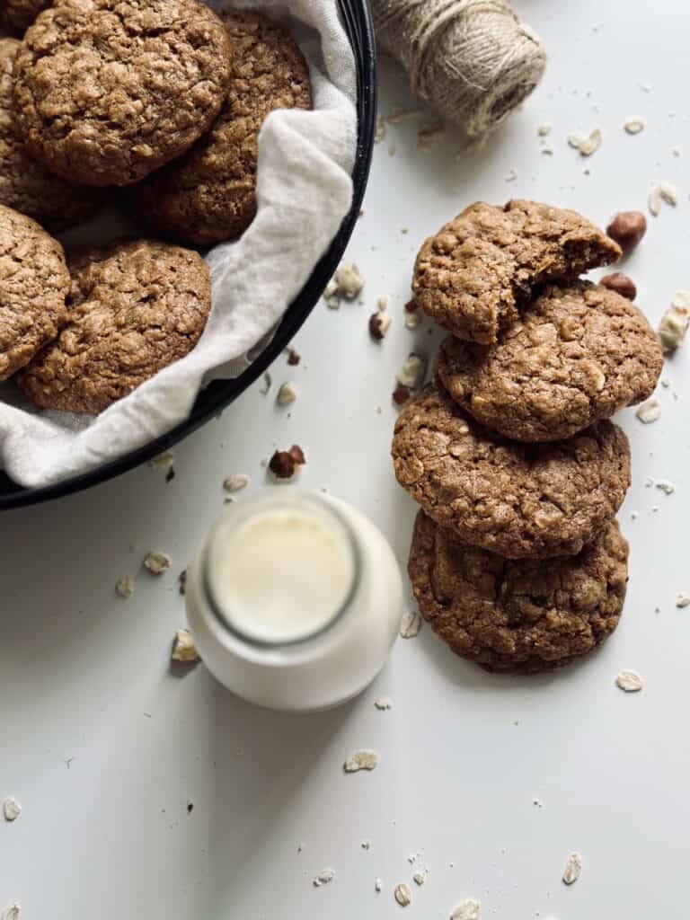 A stack of chocolate and hazelnut oat cookies next to a bottle of milk.