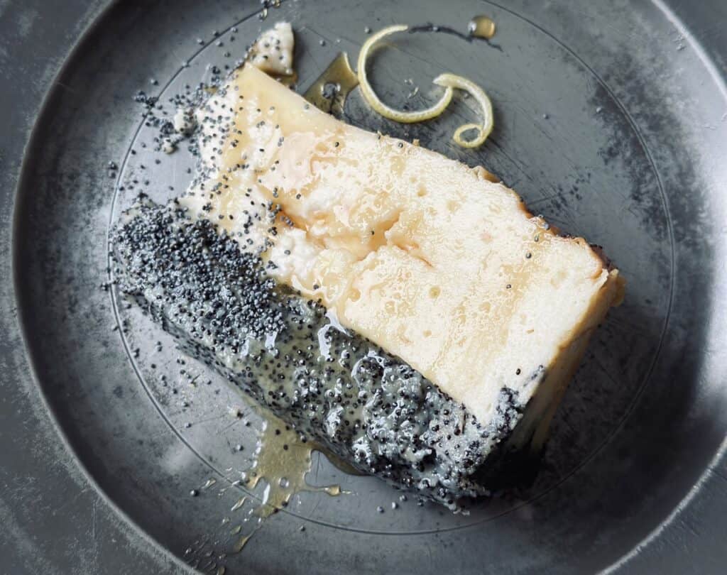 A slice of crustless poppy seed cheesecake on a vintage plate, drizzled with honey glaze .