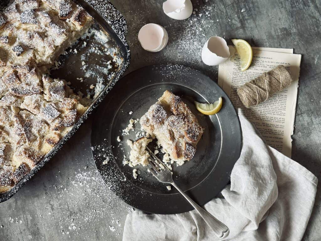 A table layout with a ricotta and lemon French toast casserole sprinkled with icing sugar.
