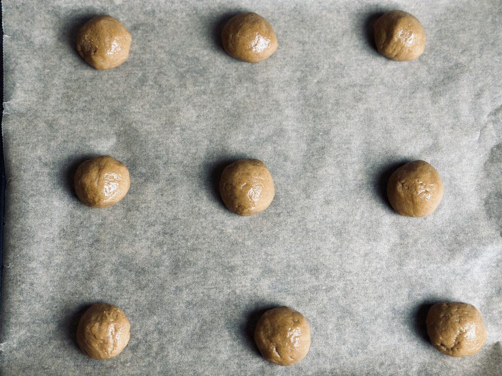 Cookie dough balls laid on a cookie sheet.