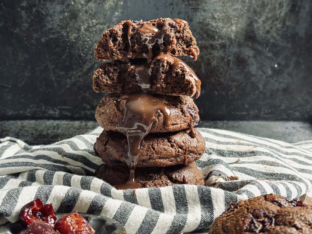 A stack of sourdough chocolate cookies with melted chocolate dripping on them.
