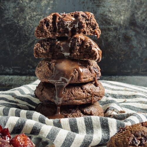 A stack of sourdough chocolate cookies with melted chocolate dripping on them.