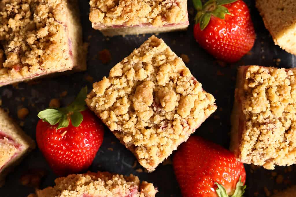 An over head shot of a sourdough strawberry coffee cake bar, surrounded by fresh strawberries.