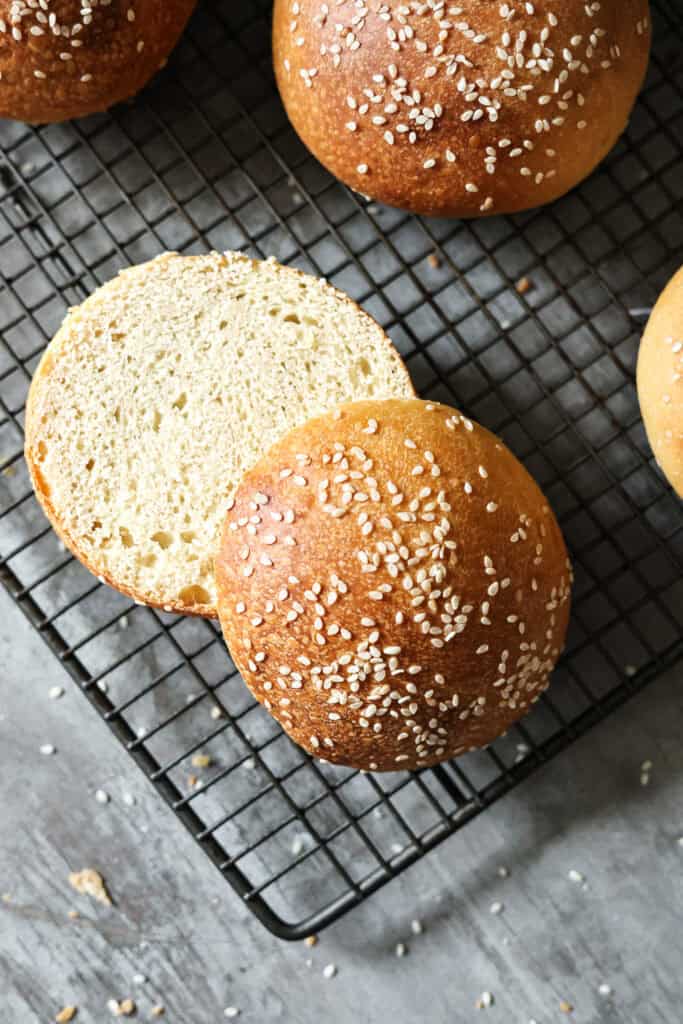 A close-up of a sliced burger bun topped with sesame seeds.