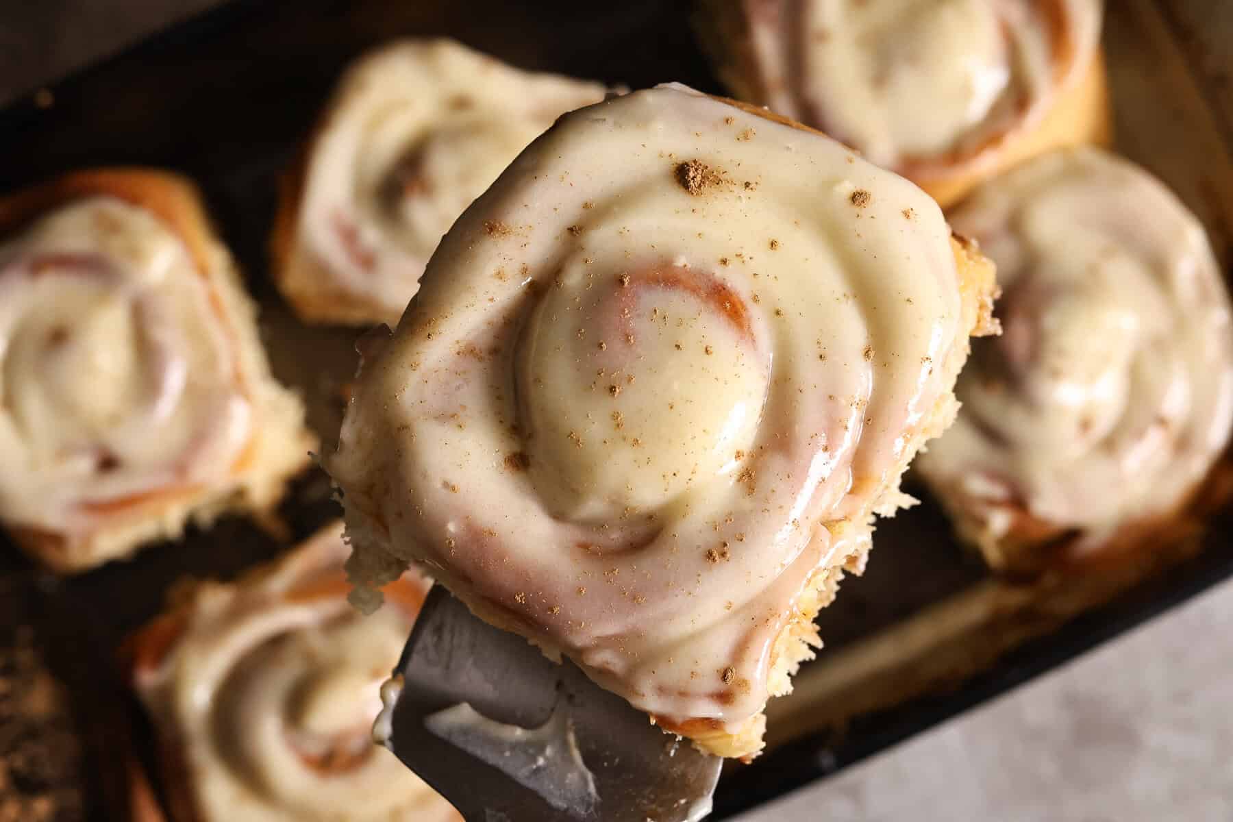 An apple cider cinnamon roll with brown butter apple filling and cream cheese vanilla icing.