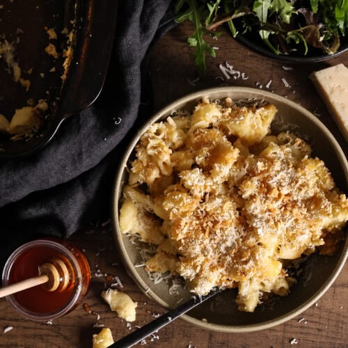 A jar of homemade hot honey next to a bowl of homemade Mac and cheese.
