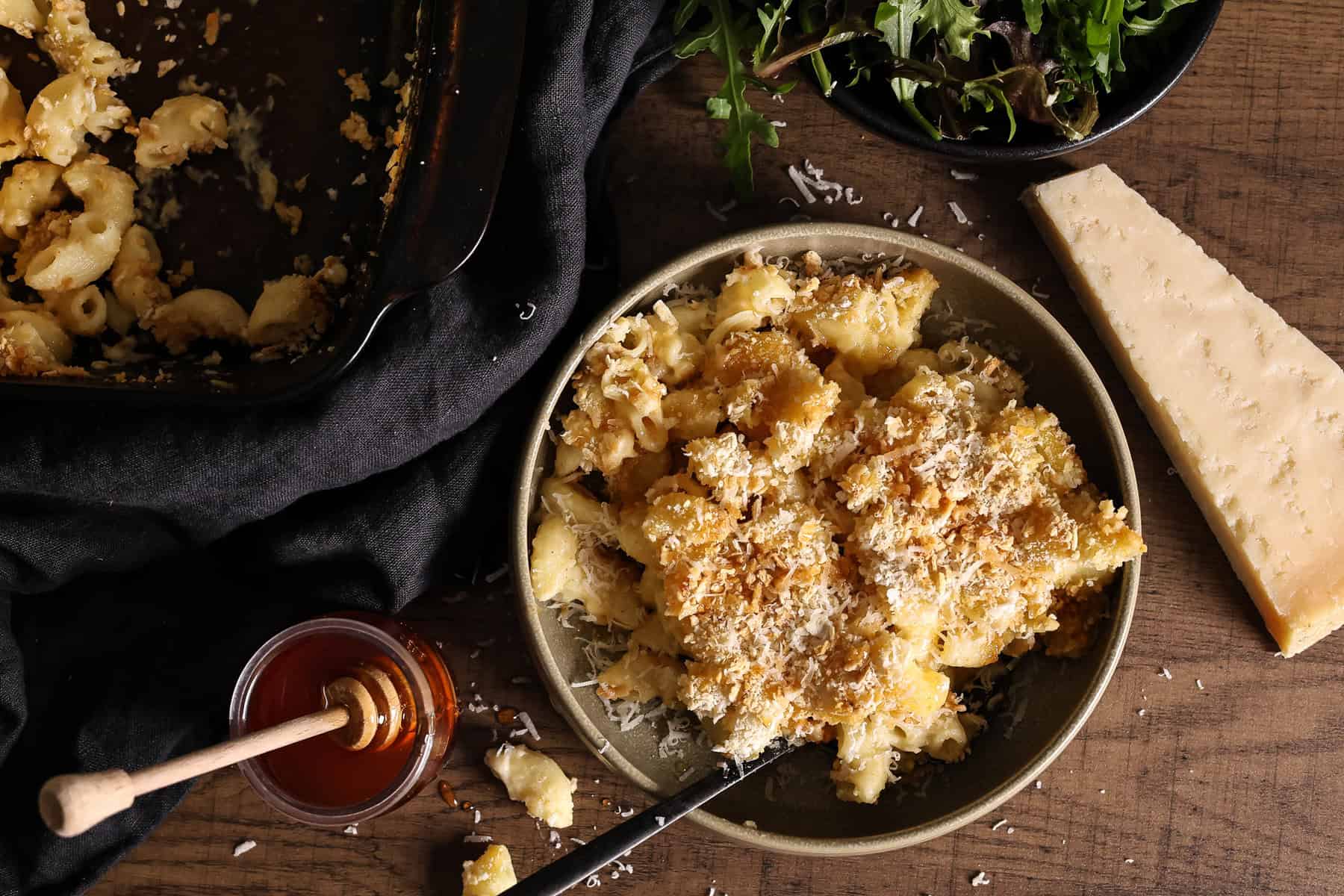 A jar of homemade hot honey next to a bowl of homemade Mac and cheese.