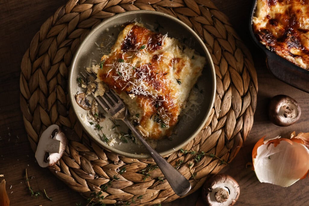 A serving of caramelized onion and mushroom lasagna with gruyere thyme cream sauce.