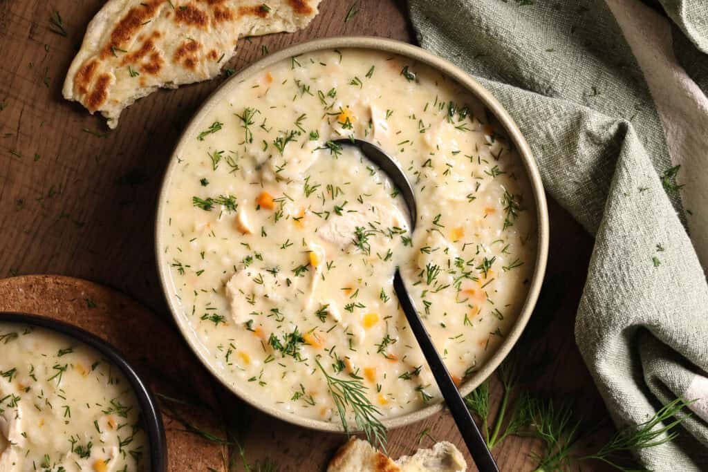 A bowl of Greek-style creamy chicken and rice soup topped with fresh dill.