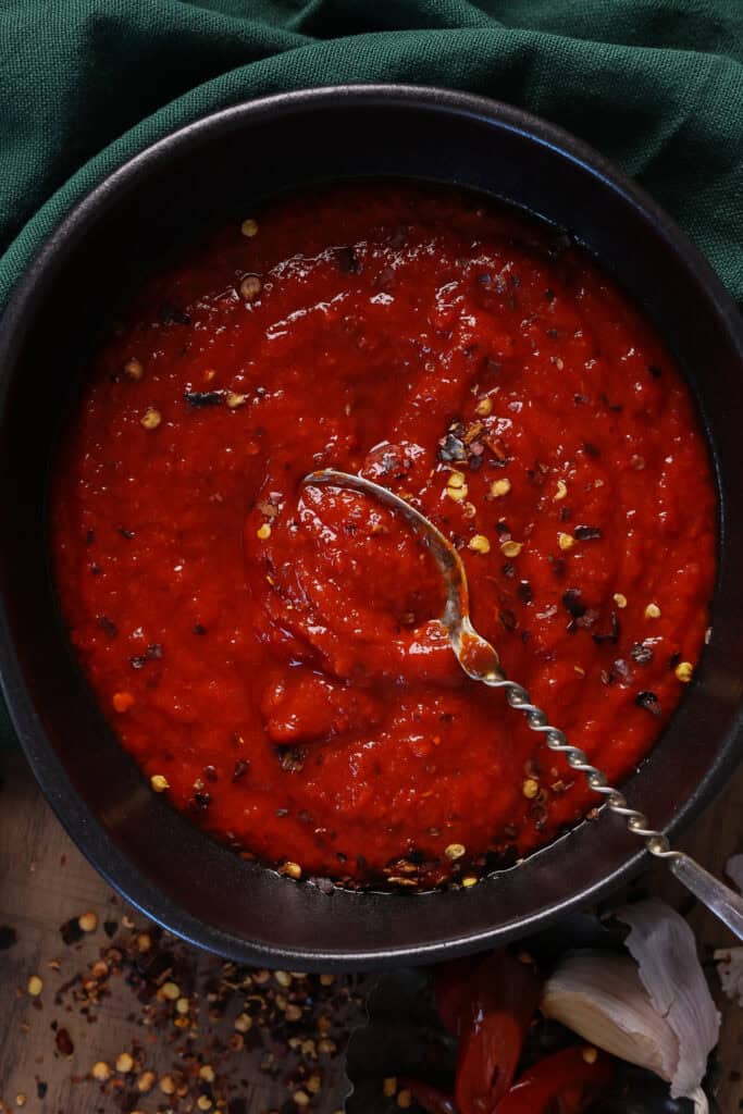 A bowl full of jalapeño hot sauce with a spoon running through it.