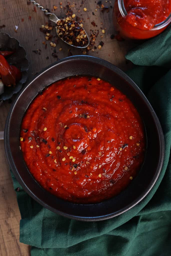 Homemade jalapeno hot sauce with roasted red bell pepper and crushed chilli flakes.