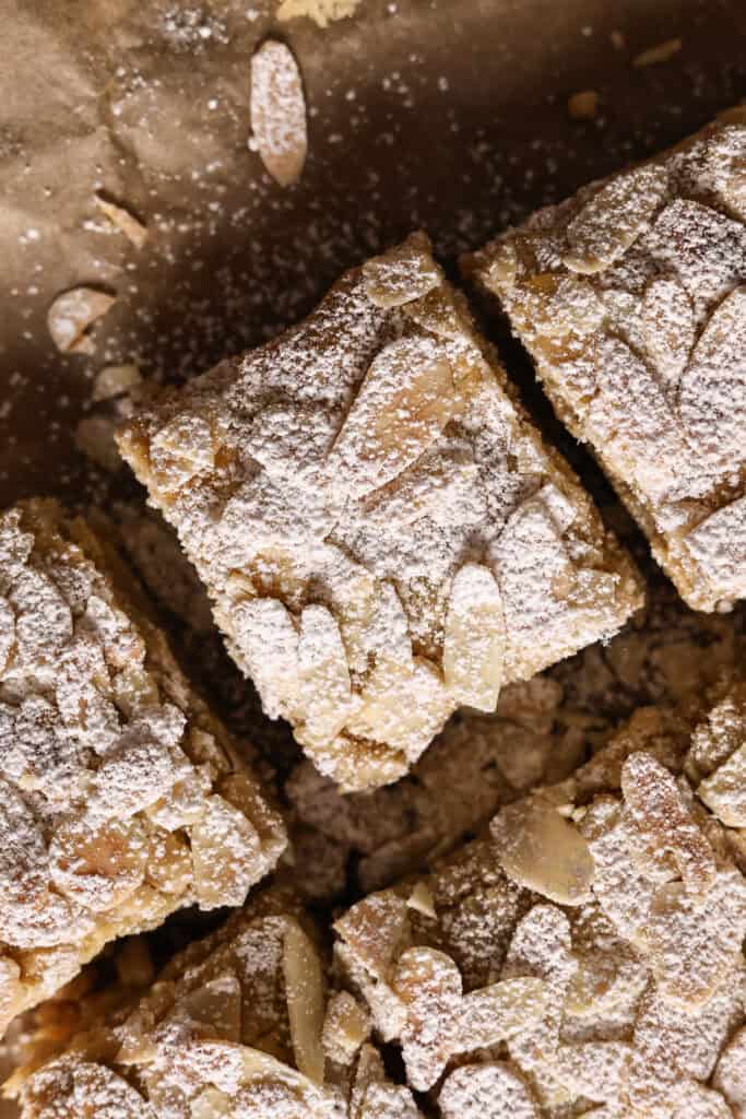 Almond cookie bar topped with sliced almonds and dusted with powdered sugar.